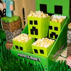 three green boxes filled with popcorn sitting on top of grass