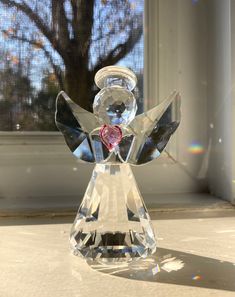 a glass angel figurine sitting on top of a counter next to a window