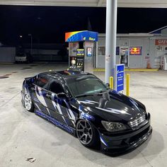 a black car parked in front of a gas station