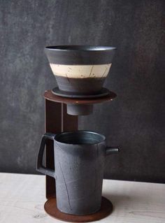 two cups are stacked on top of each other in front of a black wall and wooden stand