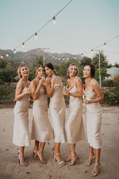 the bridesmaids are all dressed in beige dresses and high heels, posing for a photo