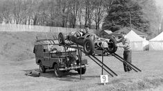 two men working on an old race car being towed by a tow truck in black and white