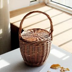 a wicker basket sitting on top of a white table next to a vase and leaves