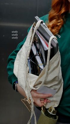 a woman with red hair carrying a bag full of files and folders in her hands