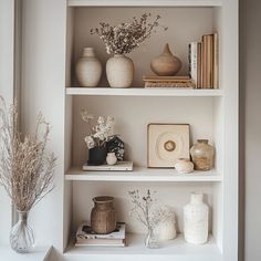 the shelves are filled with vases, books and other decorative items in white colors