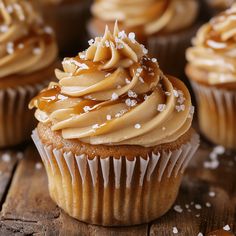 some cupcakes with frosting and sprinkles on them sitting on a wooden table