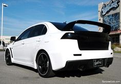 the rear end of a white car parked in a parking lot