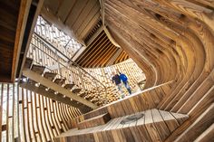 a man standing on top of a wooden stair case next to a spirally shaped staircase