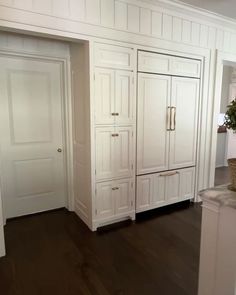 an empty kitchen with white cabinets and wood floors