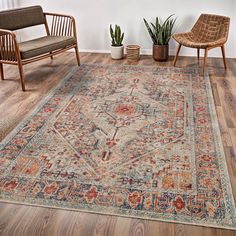 a living room area with chairs, rug and potted plants on the hardwood floor