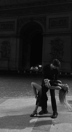 a man and woman kissing in front of a building at night with long hair blowing around them