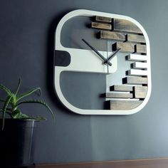 a clock made out of wood and metal on a wall next to a potted plant