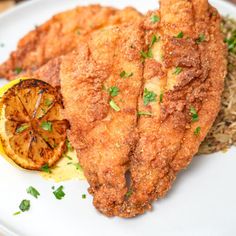 fried chicken with rice and lemon wedges on a white plate