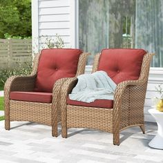 two wicker chairs with red cushions on a patio