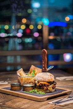 a sandwich and some french fries on a wooden table in front of a cityscape