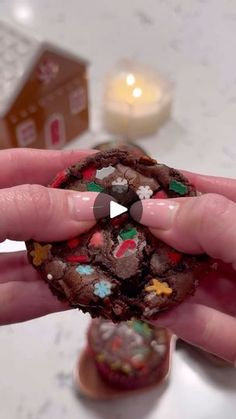 a person holding a chocolate cookie with christmas decorations on it's face and fingers