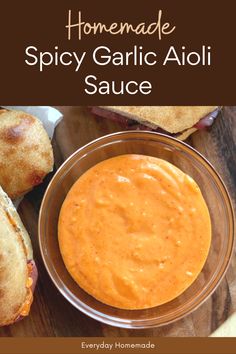 homemade spicy garlic aioli sauce in a glass bowl on a wooden table with bread rolls