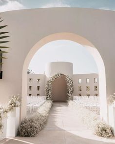 an archway leading to a wedding ceremony with white flowers and greenery on the side