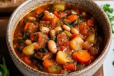 a bowl filled with beans and vegetables on top of a wooden cutting board next to parsley