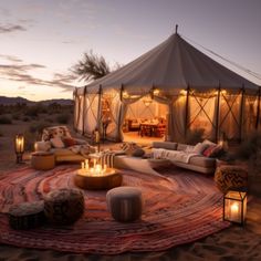 a tent set up in the desert with candles lit on it's floor and couches