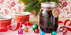 a jar filled with liquid sitting on top of a table next to two mugs