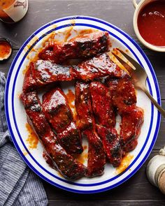 a plate full of ribs covered in sauce and ketchup with a fork on the side