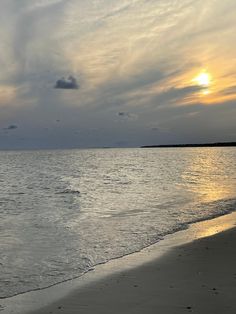 the sun is setting over the water at the beach