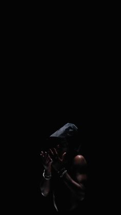 a woman standing in the dark holding her hands to her face