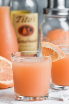 two glasses filled with orange juice next to bottles