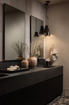 a bathroom with two vases on the counter and mirrors in the wall above it