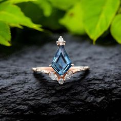 a blue topazte and diamond ring on a black surface with leaves in the background