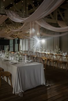 a long table is set up with white linens and candles for an elegant wedding reception