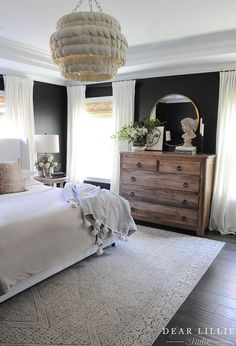 a bedroom with black walls and white bedding is decorated in neutral tones, such as linens