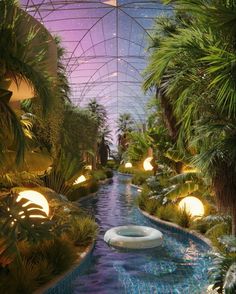 an indoor swimming pool surrounded by palm trees and other greenery, with lights on the ceiling