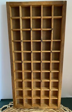 an old wooden bookcase sitting on top of a woven tablecloth covered floor next to a white wall