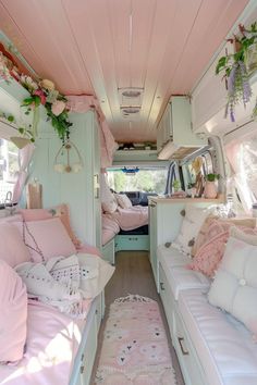 the interior of a camper with pink and white decor on the walls, couches, and bedding