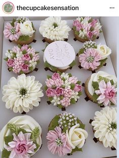 a box filled with cupcakes covered in frosting and decorated with pink and white flowers