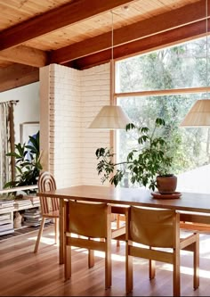 a dining room table with two lamps hanging from it's ceiling and chairs around it