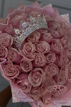 a bouquet of pink roses with a tiara on top is being held by someone's hand