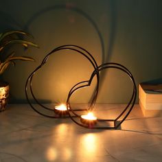 two heart shaped candles sitting on top of a table next to a potted plant