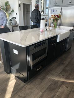 two men are standing in the kitchen with an island