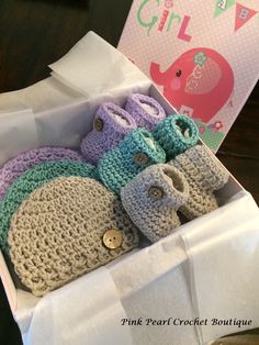 there are four pairs of crocheted baby shoes in a box with a girl card