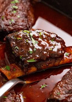 a close up of some meat on a plate with sauce and green garnish