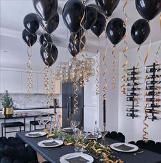 black balloons are hanging from the ceiling above a dining room table with plates and silverware