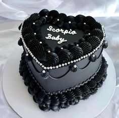 a black heart shaped cake with the words scorpion baby written on it's side