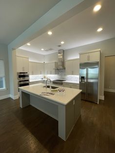 a large kitchen with an island in the middle and stainless steel appliances on both sides