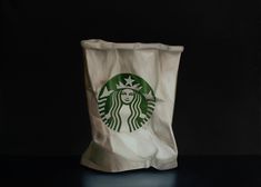 a starbucks bag sitting on top of a black table next to a white cup filled with coffee