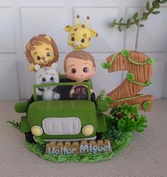 a green toy truck with animals in the back and on top, sitting next to a tree