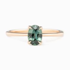 an oval cut green tourmaline gemstone ring in yellow gold, on a white background