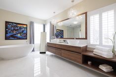 a bathroom with a tub, sink and large mirror